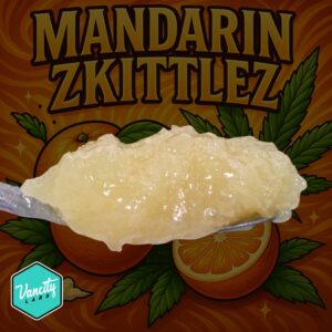 Close-up of Mandarin Zkittlez Full Spectrum Extract – golden dab with citrus-themed background, highlighting premium cannabis concentrate.